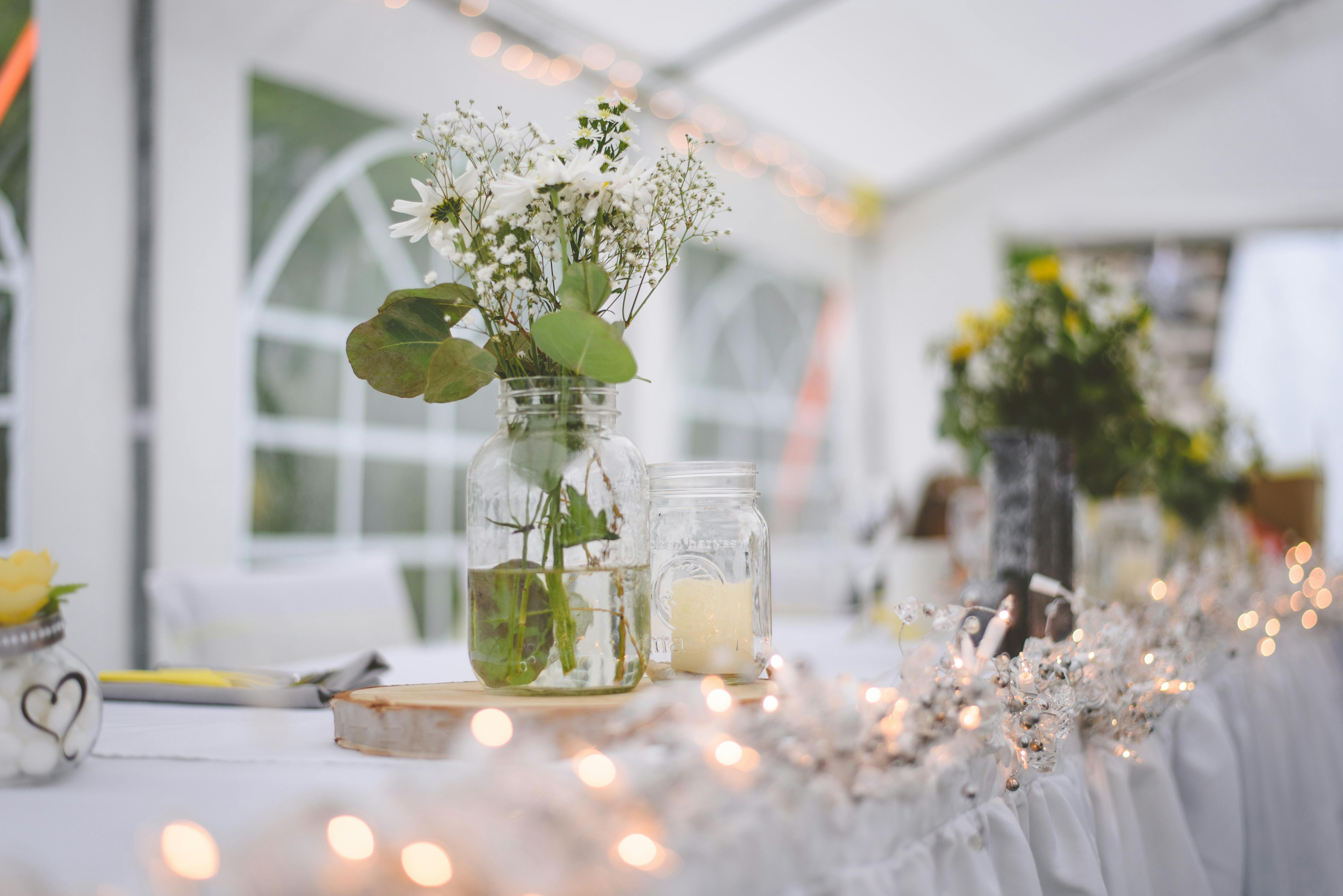 bild på bröllopslokal i ett tält med blommor och belysning på bordsdukningen