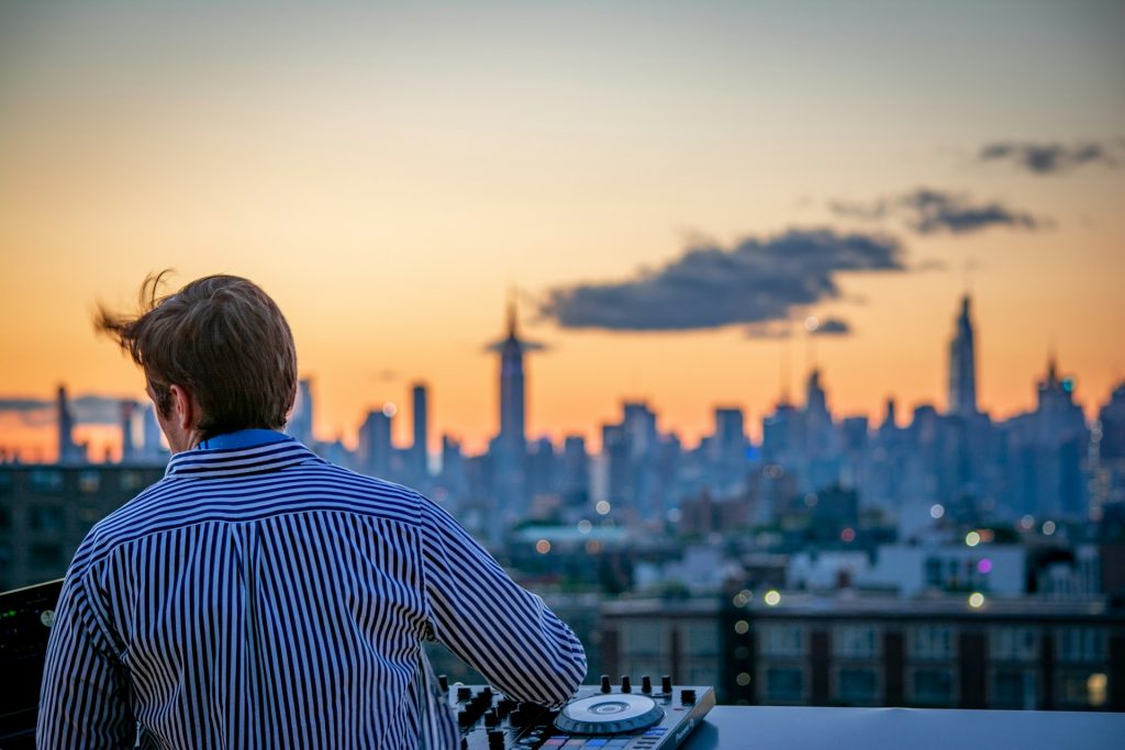 DJ playing on the instrument while watching the sunset over the city